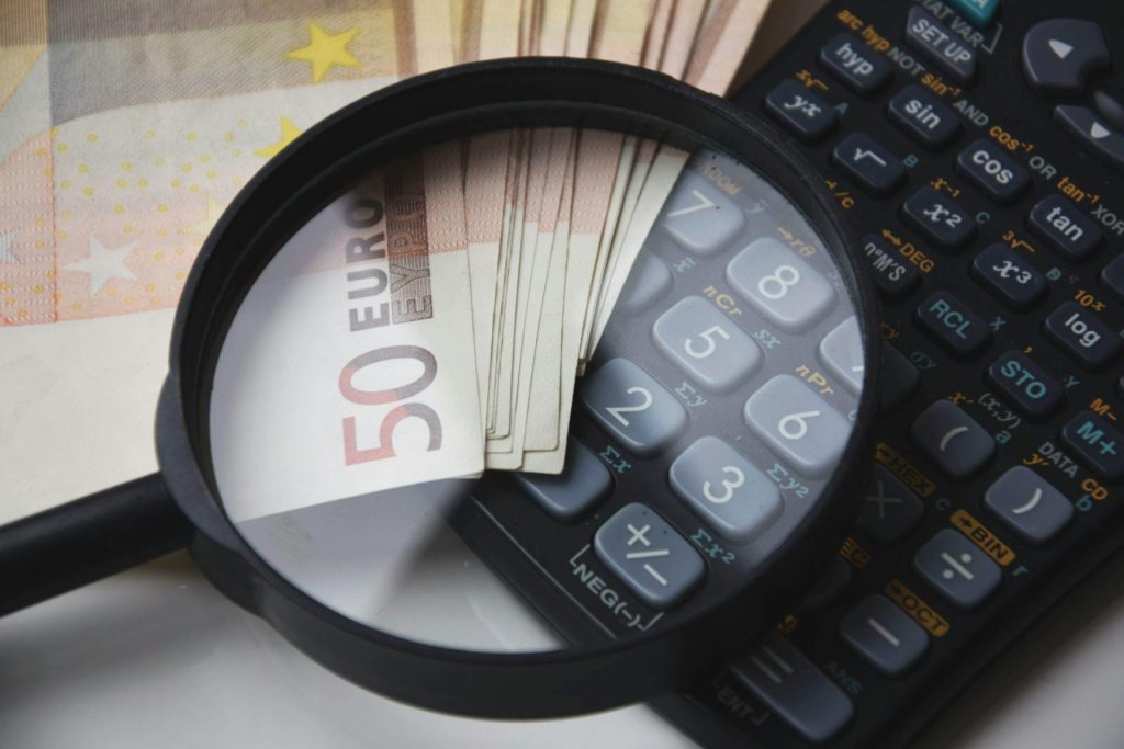 loupe avec billet argent et calculatrice qui représente les économies d'argent