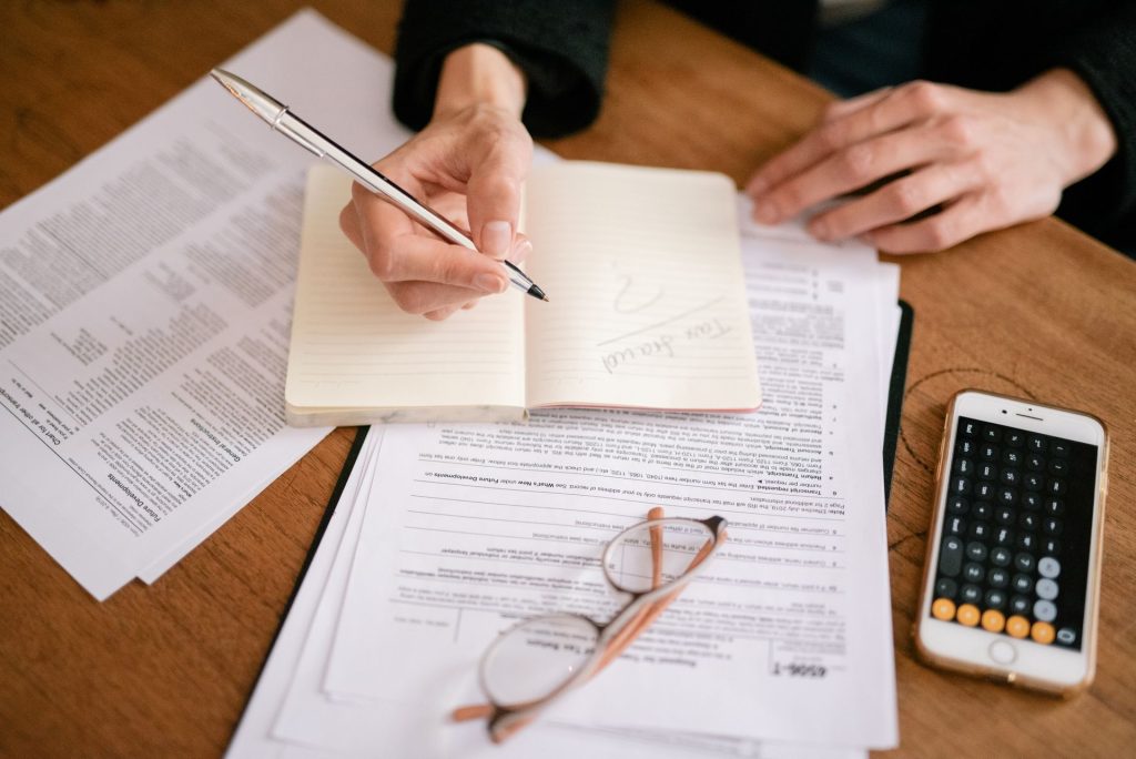 personne travail sur papier avec calculatrice et écrit sur un cahier
