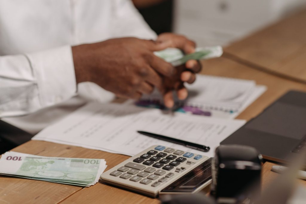homme assis sur un bureau avec argent entre les mains et une calculatrice