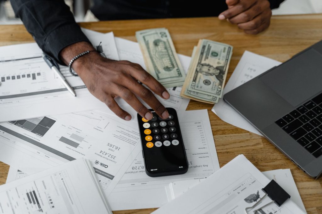 homme compte billet banque avec calculatrice sur son telephone