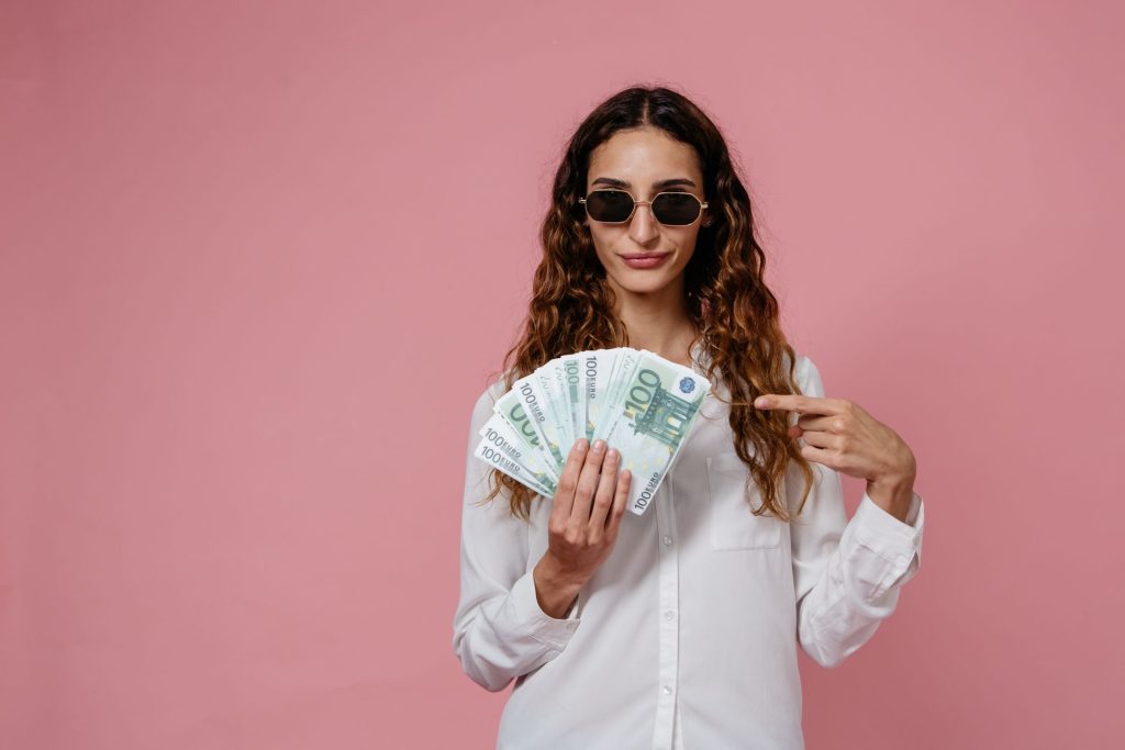 femme avec lunettes de soleil qui pointe avec son doigt des billets de banques