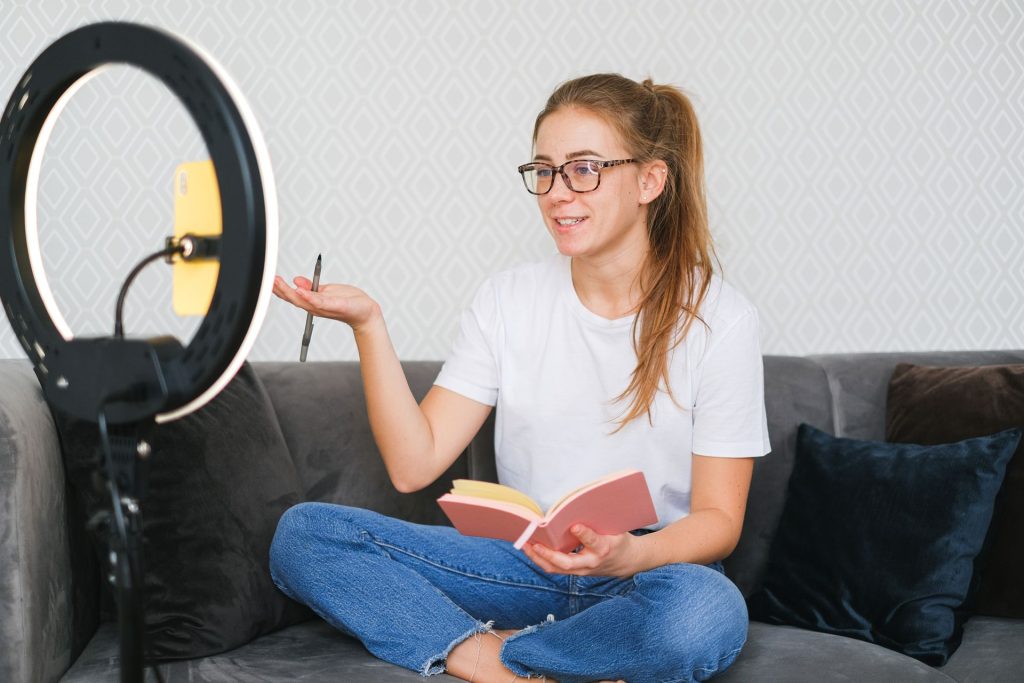 photo d une influenceuse devant une ringlight avec son telephone assise en tailleur