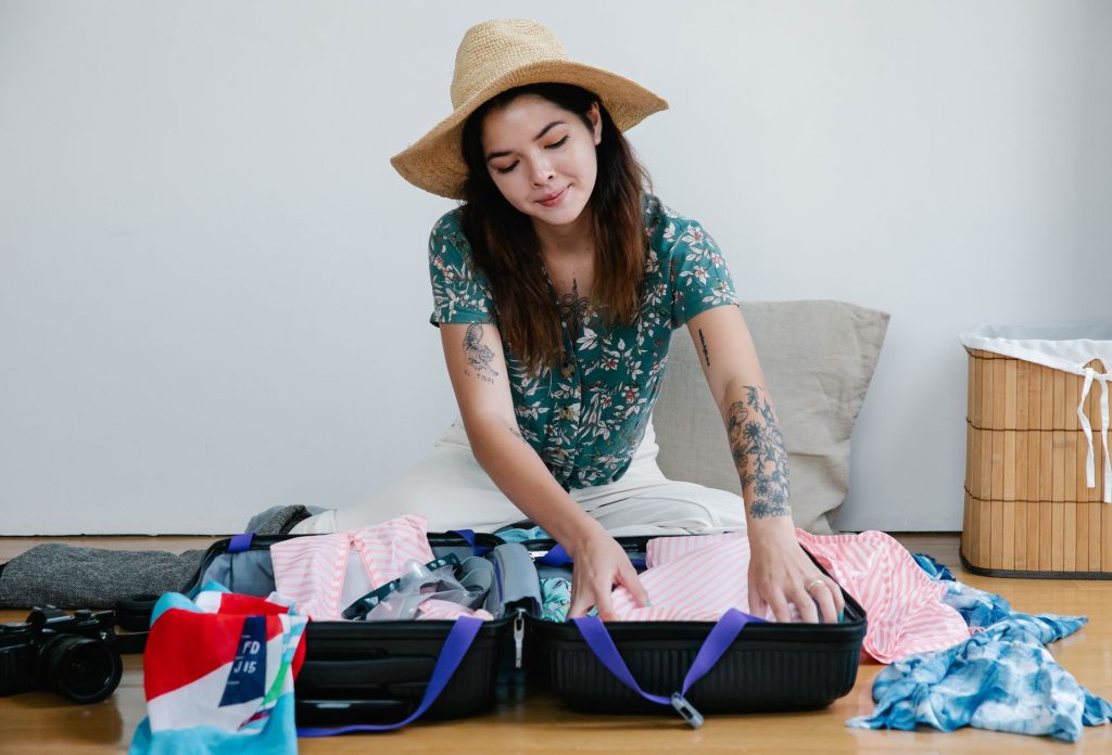 femme qui fait ses valises avec un chapeau sur la tête